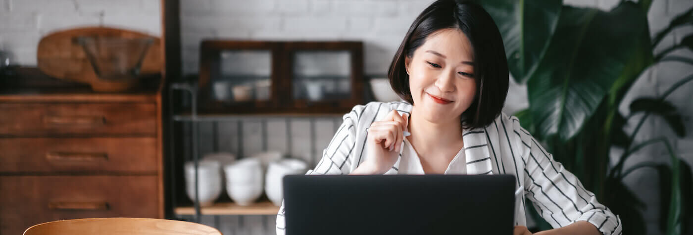 A woman smiling while working on her laptop