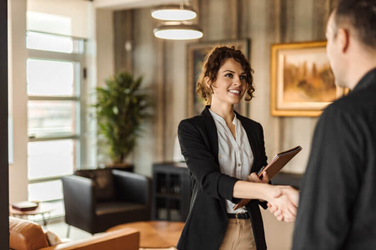 Two individuals smiling and shaking hands