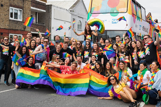 The Qualtrics team, posed as a group in front of the Qualtrics + SAP double decker Pride bus, at the 2019 Dublin Pride parade