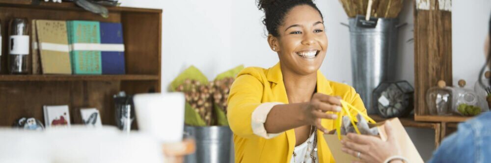 Smiling woman handing a customer their purchase