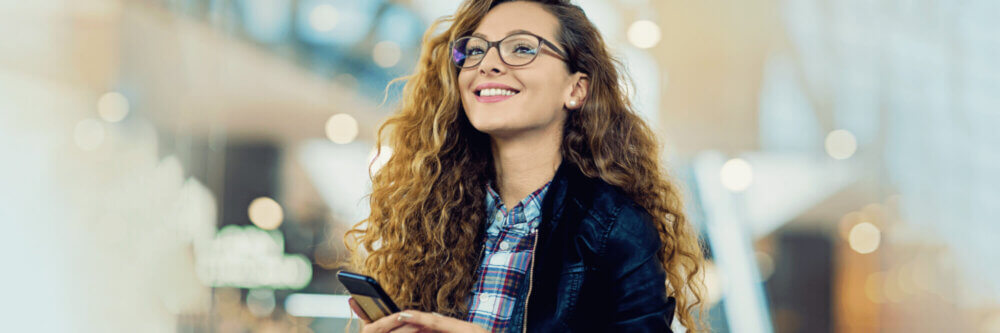 Woman with glasses holding her smartphone