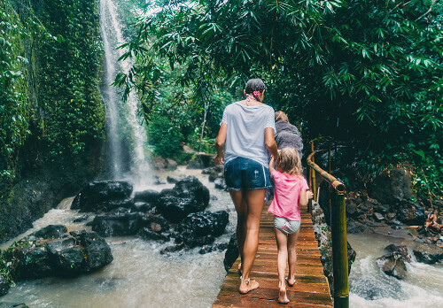 Mother and daughter crossing footbridge to waterfall