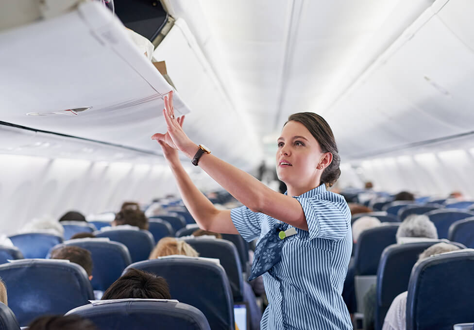 Airline employee closing overhead baggage containers