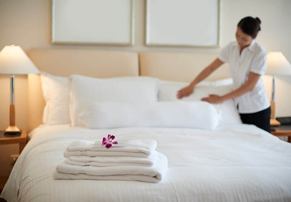 Hotel employee making bed in room