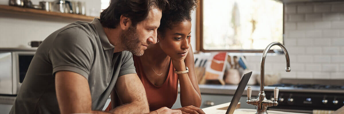 A couple searching on a computer in the kitchen