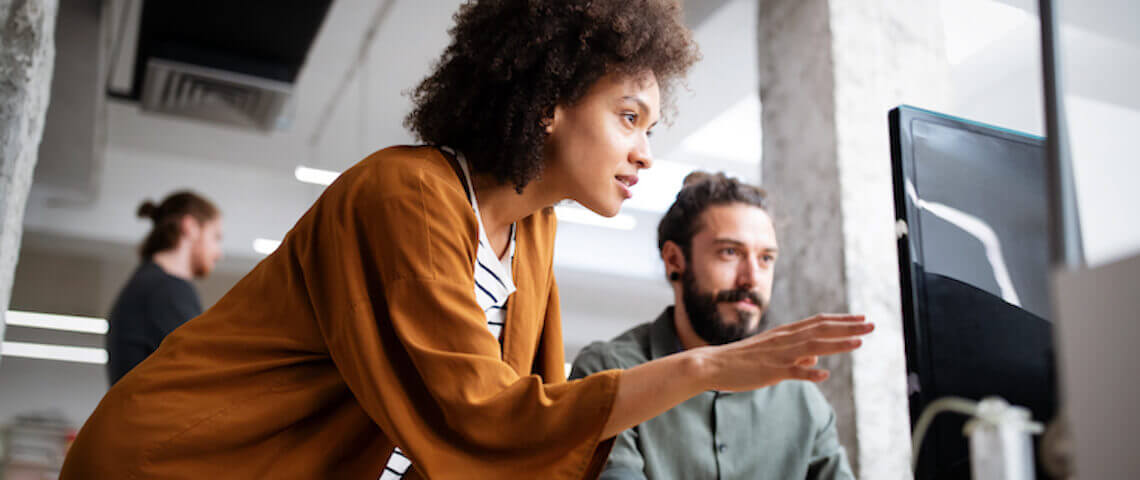 A woman pointing to a screen explaining something to a man