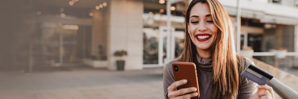 Smiling woman holding her phone and a credit card