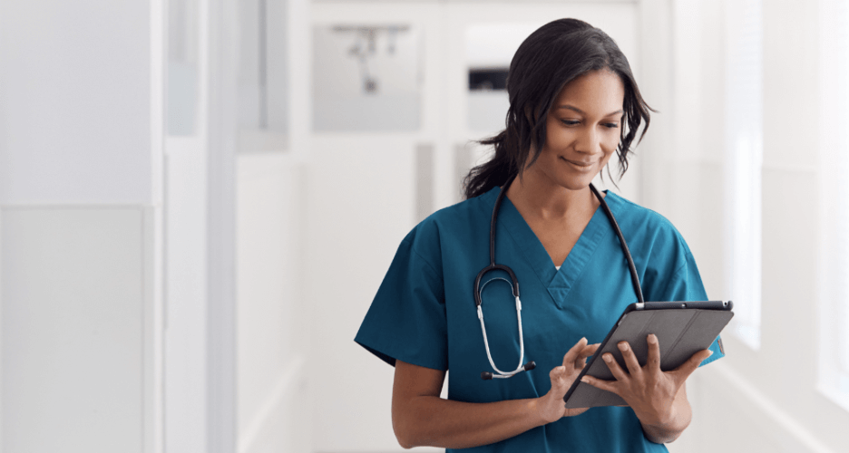 A nurse acting on patient experience insights while smiling at a screen