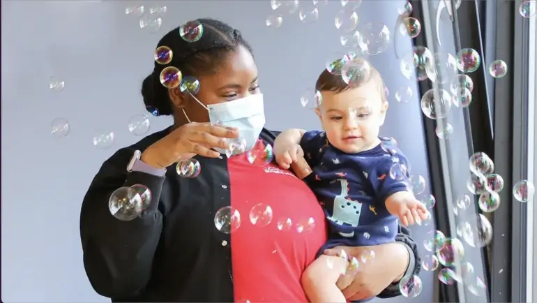 A babysitter playing with a kid and bubbles. 