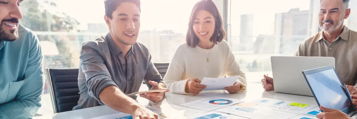 A graphic of two men and a woman discussing charts on a table