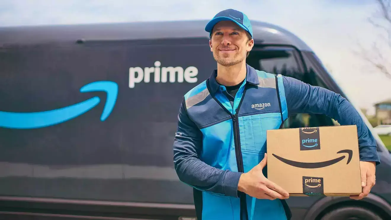 Amazon delivery driver holding package in front of van