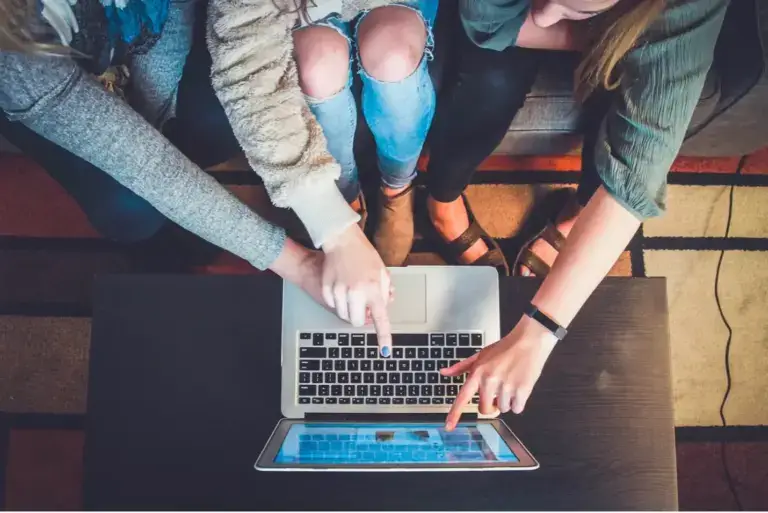 people looking at and pointing to a computer