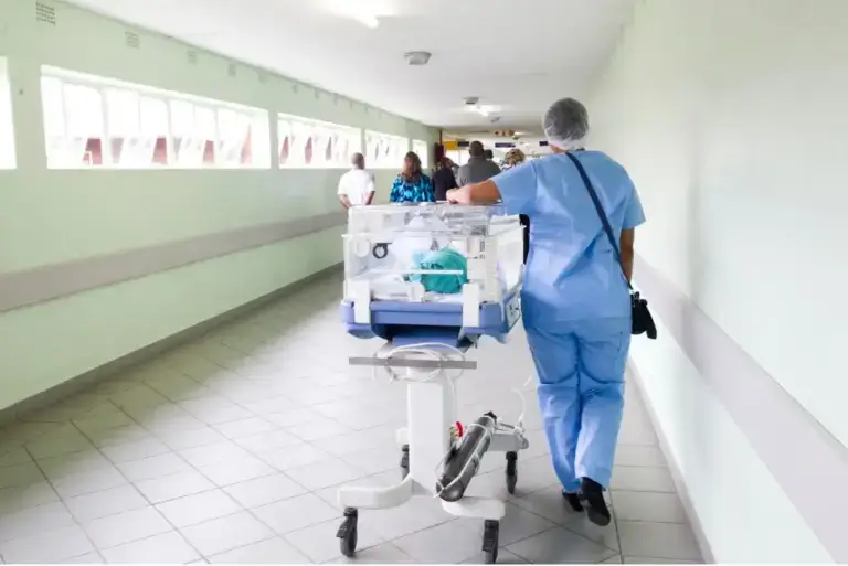 medical provider wheeling a patient down a hallway