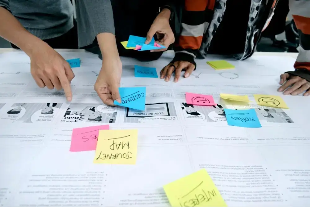 Hands arranging colorful sticky notes on documents during a planning session