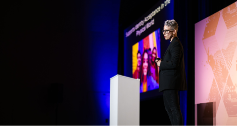 Speaker presenting breakout strategy session on X4 Summit stage with presentation screens