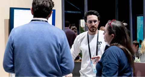 Three professionals networking in conversation at X4 Summit