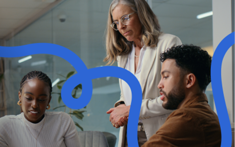 Three colleagues collaborating in a modern office, with Qualtrics blue brand graphics overlaid.