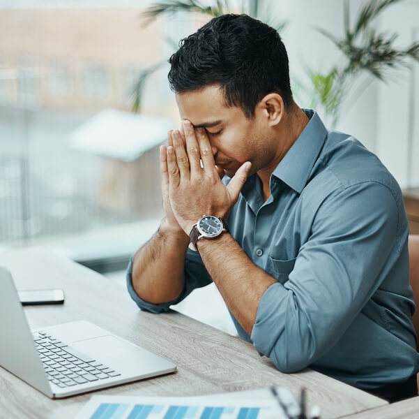 Man holding head in frustration at desk