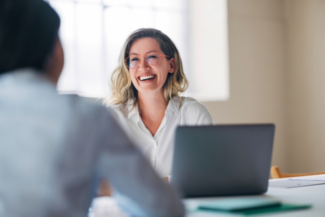 Highly engaged and smiling woman in office setting during business meeting.