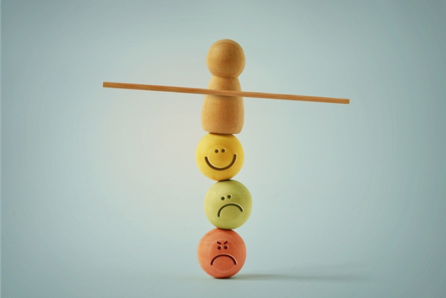 Wooden pawn balancing on beads faces with different mood expressions - Concept of likert scale.