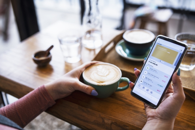 Woman managing bank account on smartphone at cafe.