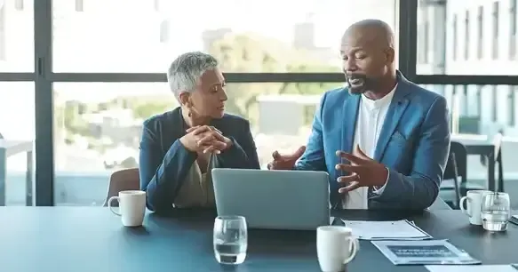 Man and woman discussing employee turnover behind a laptop