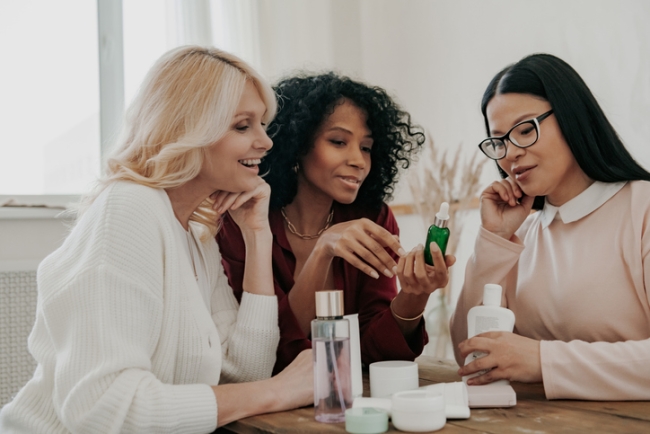 Group of women reviewing beauty and skincare products in bright, modern setting