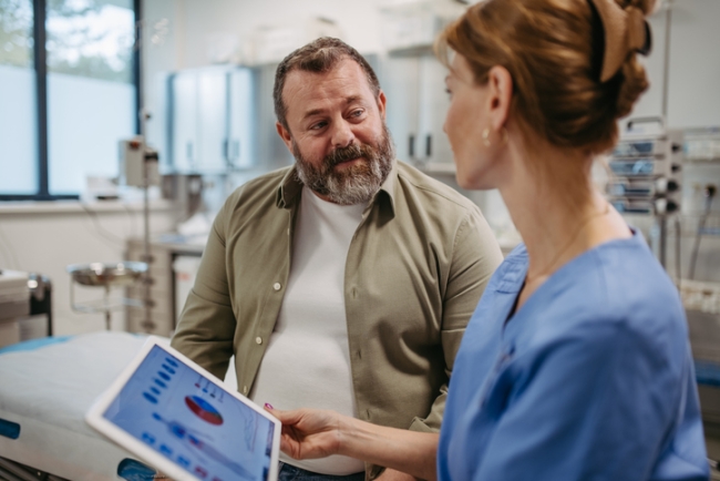 Medical professional discussing health data on tablet with patient in clinic