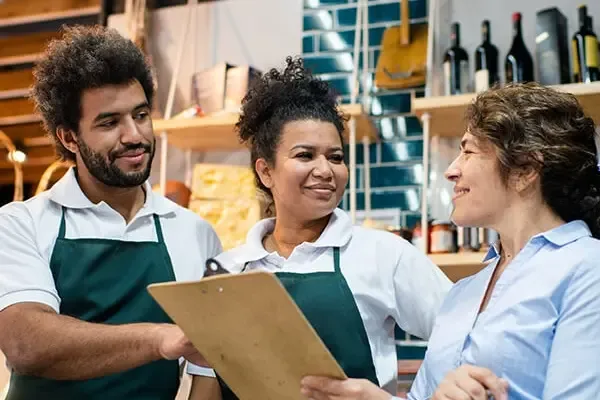 Retail employees talking, one holding a clipboard