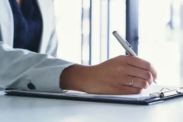 Person filling out a survey with a clipboard and pen