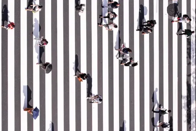 A top-down view of people crossing a striped zebra crossing