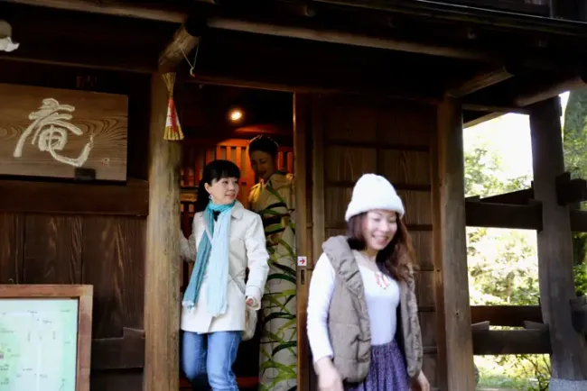 晴れた日に日本の伝統的な木造建築から出てくる3人の女性。