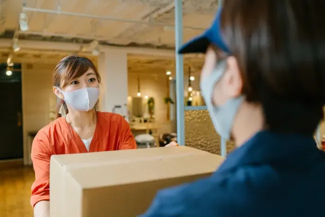 オフィスの入口で配達員から荷物を受け取る女性。