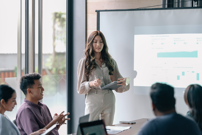 Businesswoman giving presentation to colleagues in meeting room.