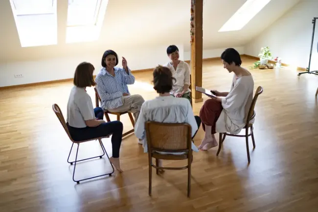 日当たりの良い部屋で輪になって座り、話し合いをする女性たちの小グループ。