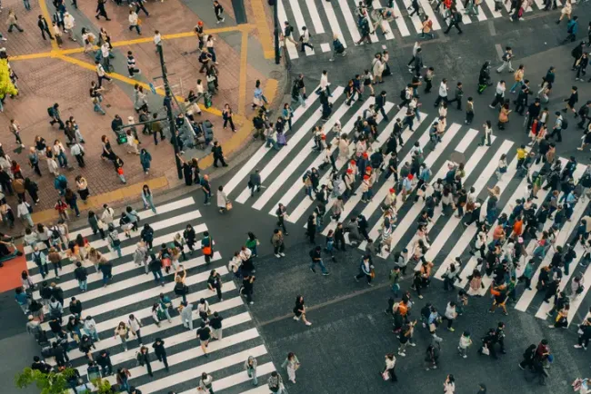 混雑した都市部の交差点を渡る歩行者たちの俯瞰図。