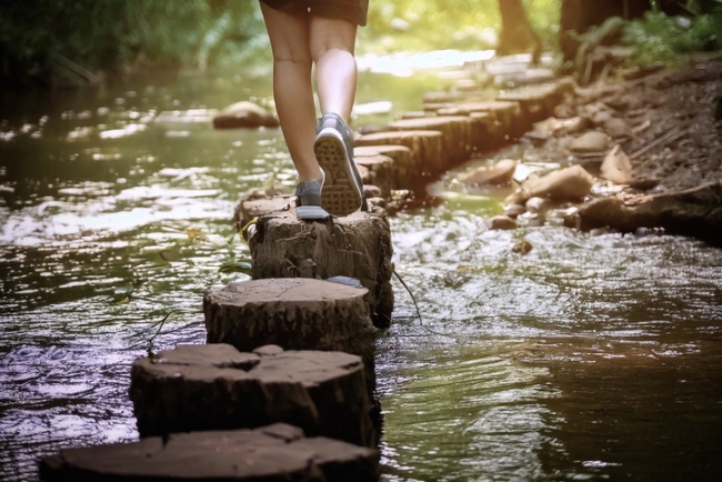 Person walking across a river on stepping stones.