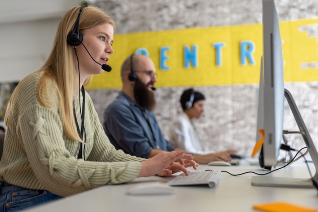 Group of contact center employees working with computers and headsets.
