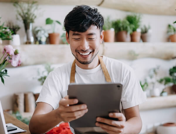 Florist checking order on his tablet in shop.