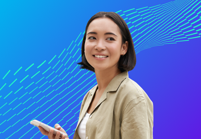 Woman holding mobile phone while looking over her shoulder towards the reader.