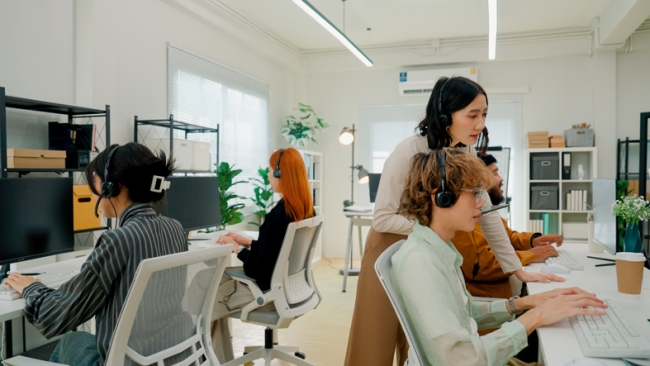 Customer care team working in their office with the supervisor overseeing the environment. 
