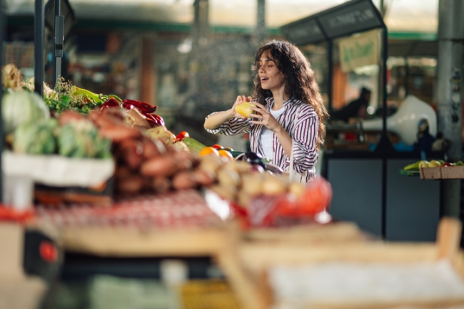 Young woman smelling a fresh fruit at the farmers market.
