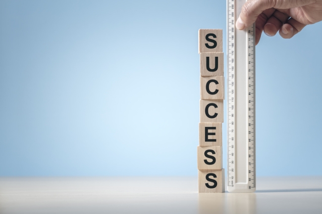 Ruler measuring wood blocks making up the word success.