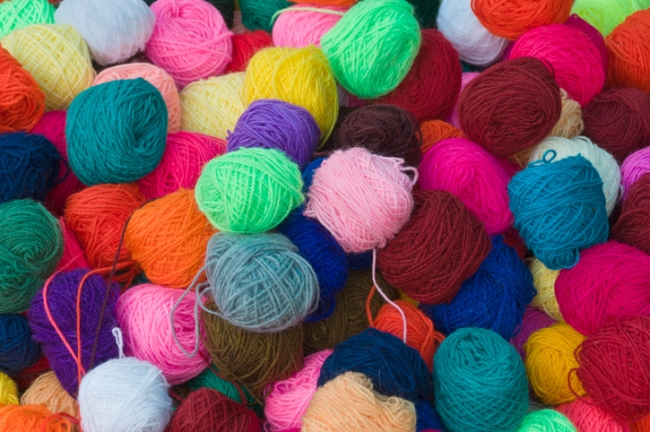 Brightly coloured collection of wool on sale in a market.