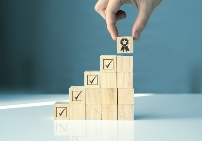 Stacked wooden blocks with check marks creating stairway to represent improvement in customer service.