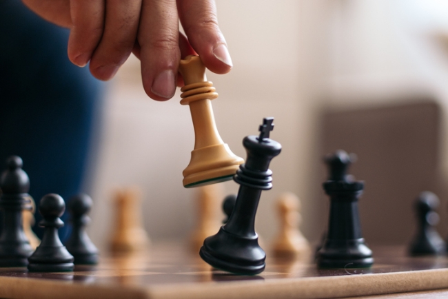 Hand of an unrecognizable man playing chess and taking his opponent's bishop.