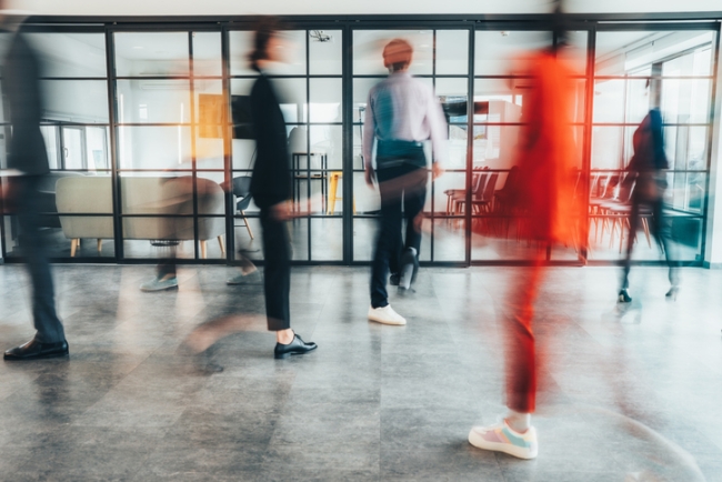 Blurred motion, group of people walking fast in the office lobby.