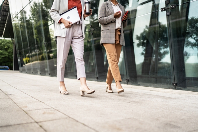 Business women walking and talking on city pavement during walking meeting.
