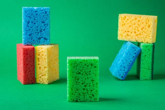 Multicolored sponges stacked as geometric blocks, on green paper background, representing data saturation.