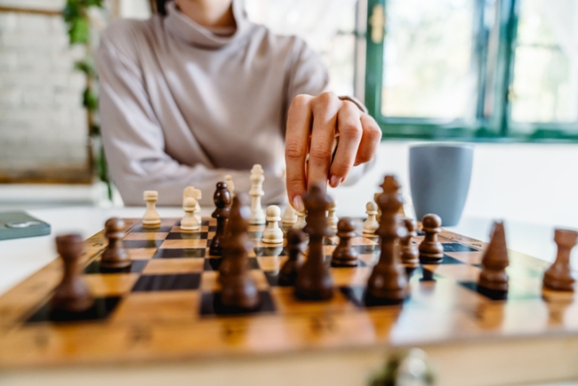 Woman making a strategic move during a chess game at home.